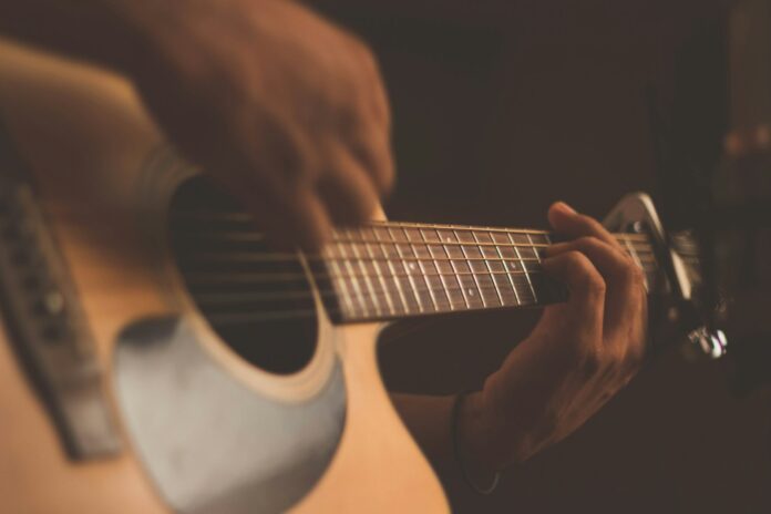 Woman playing acoustic guitar in warm light — spirit through song